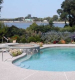 Freeform pool with raised wall and spa overflow.