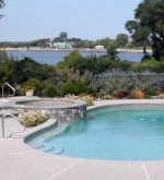 Freeform pool with raised wall and spa overflow.