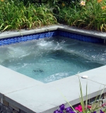 10' x 10' gunite spa with a stone veneer exterior with bluestone coping and automatic cover.