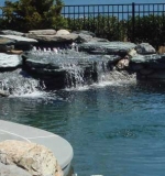 Natural boulders set on shelves below water level with 6' high cascading waterfall.